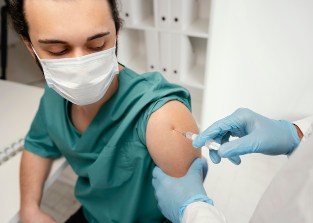 Foto grátis médico vacinando um paciente na clínica