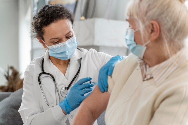 Médico vacinando uma mulher idosa