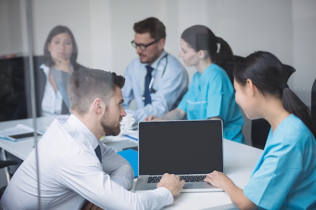 Médicos discutindo sobre laptop em reunião