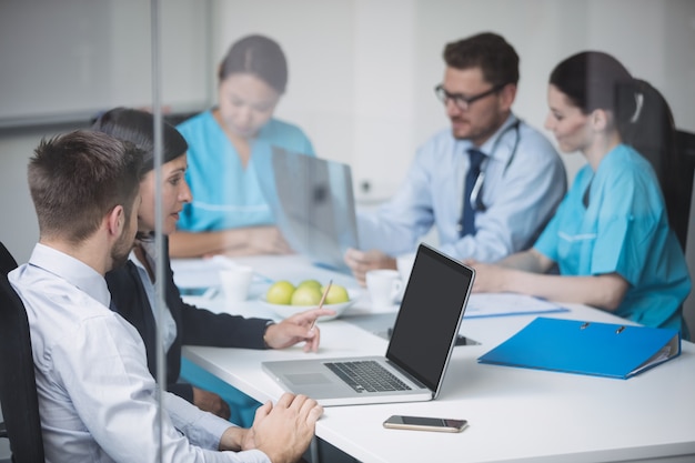 Médicos discutindo sobre laptop em reunião