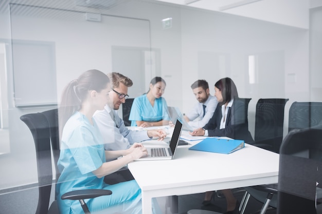 Médicos discutindo sobre laptop em reunião