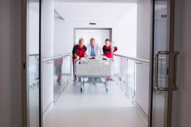 Médicos empurrando cama maca de emergência no corredor
