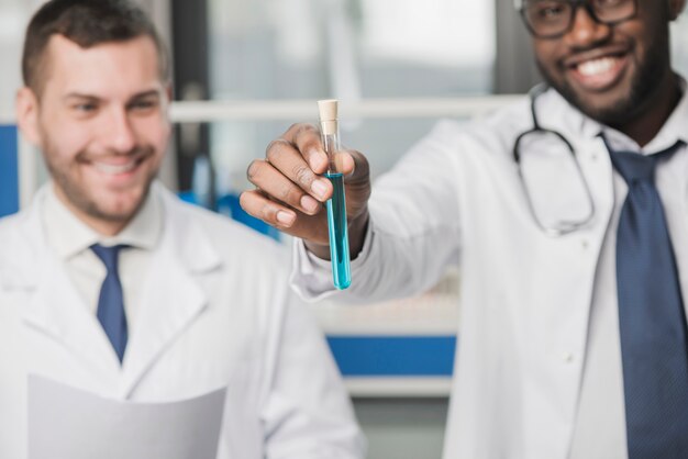 Médicos multiraciais alegres com tubo de ensaio