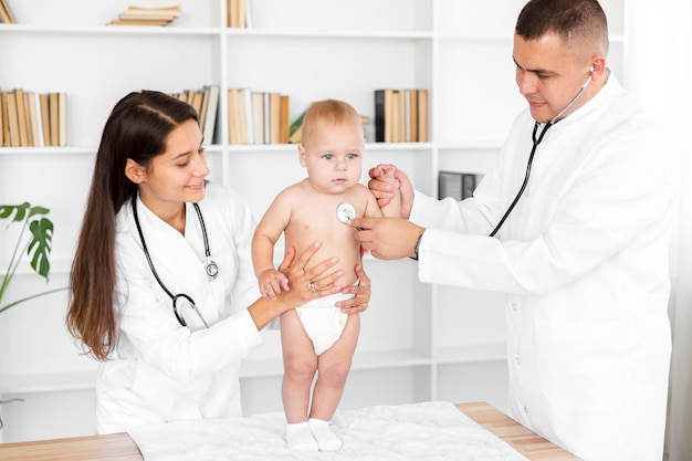 Foto grátis médicos ouvindo adorável bebê com estetoscópio