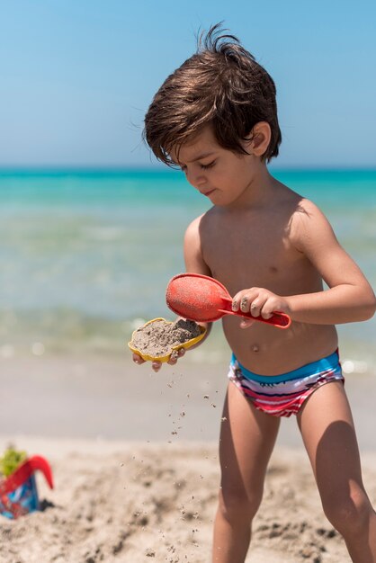 Médio, tiro, criança, tocando, areia, praia