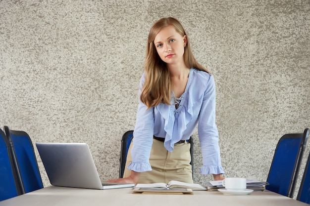 Médio, tiro, de, um, businee, senhora, ficar, em, escrivaninha escritório, olhando câmera