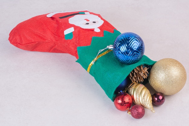 Meia de Natal cheia de bolas festivas na superfície branca