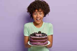 Foto grátis meia dose de dente doce feminino com cabelo afro, segurando um delicioso bolo doce no prato