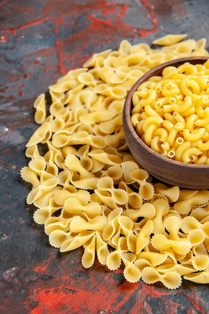 Meia dose de macarrão com borboletas em uma tigela marrom na mesa de cores diferentes