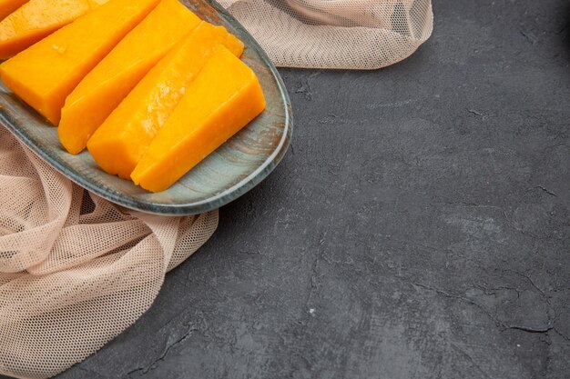 Meia dose de queijo amarelo fresco natural em uma toalha meio dobrada em um fundo preto