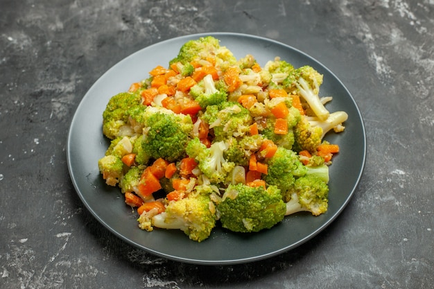 Foto grátis meia dose de refeição saudável com brocoli e cenoura em uma placa preta na mesa cinza