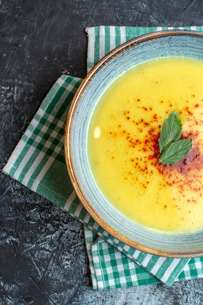 Meia dose de uma panela azul com sopa saborosa servida com hortelã em uma toalha verde despojada sobre fundo azul