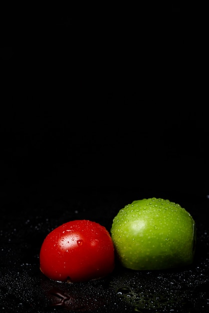 Meia maçã e tomate em um preto