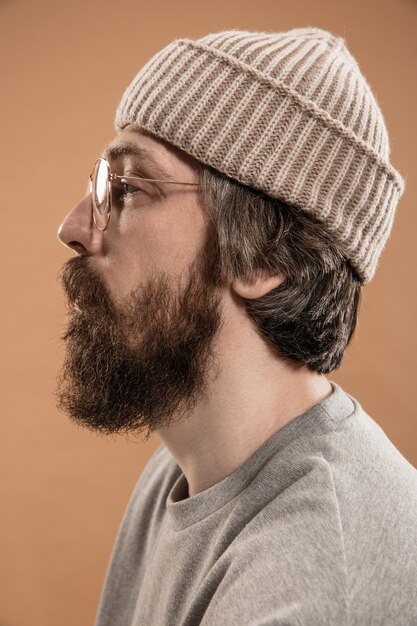 Meia retrato de um homem branco de óculos e chapéu isolado sobre uma parede amarela clara. Bigode e barba. Conceito de emoções humanas, expressão facial, anúncio, moda. Copie o espaço