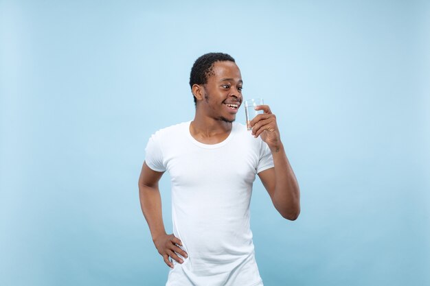 Meio comprimento close-up retrato de jovem afro-americano em camisa branca no espaço azul