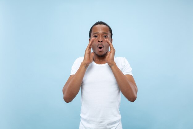 Meio comprimento close-up retrato de jovem afro-americano em camisa branca no espaço azul