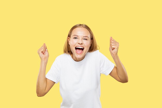 Meio comprimento do retrato de mulher jovem caucasiana em fundo amarelo do estúdio. Linda modelo feminina em camisa branca