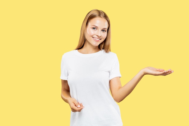 Meio comprimento do retrato de mulher jovem caucasiana em fundo amarelo do estúdio. Linda modelo feminina em camisa branca