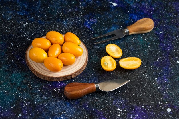 Foto grátis meio corte e enquanto kumquats na superfície azul