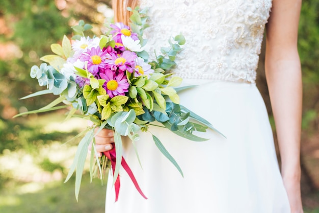 Meio de mão de uma noiva segurando buquê de flores