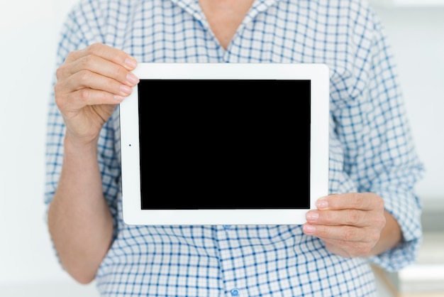 Meio de mulher mostrando tablet digital com tela em branco