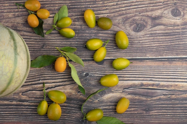 Melão branco e frutas frescas de kumquat na mesa de madeira.