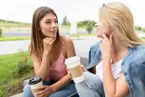 Foto grátis melhores amigas de frente segurando alguns copos de papel de café