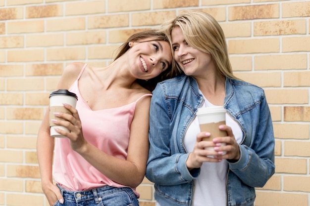 Melhores amigas posando com suas xícaras de café