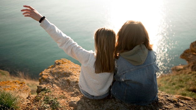 Melhores amigas se abraçando e oceano