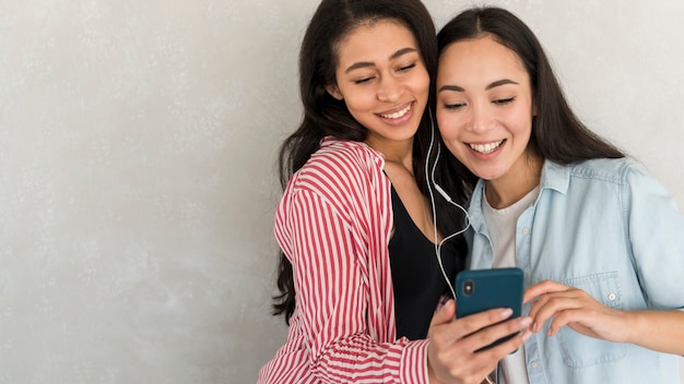 Melhores amigas usando smartphone em fones de ouvido