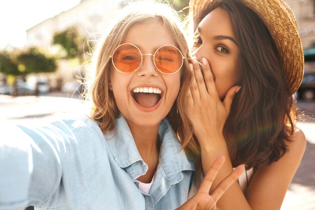 Melhores amigas vestindo roupas elegantes e tirando selfie na rua