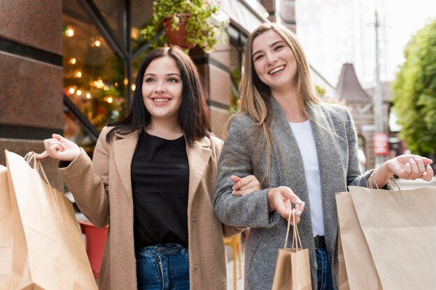 Melhores amigos segurando sacolas de compras do lado de fora