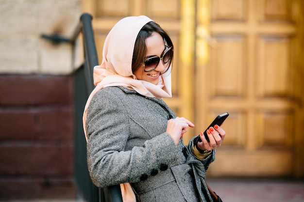 Foto grátis menina à moda que sorri com seu celular