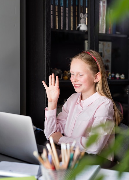 Menina acenando para seus colegas através de sua câmera web