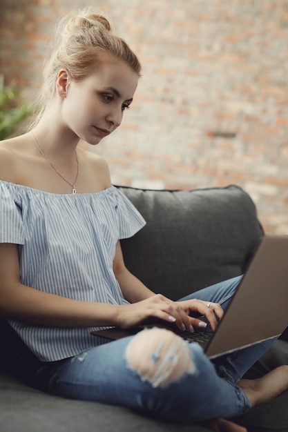 Menina adolescente bonita com laptop, sentado no sofá