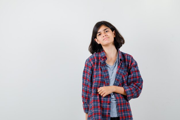 Menina adolescente em camisa quadriculada e olhando melancólica, vista frontal.