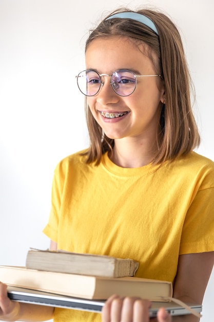 Foto grátis menina adolescente engraçada com livros e laptop no fundo de uma parede branca