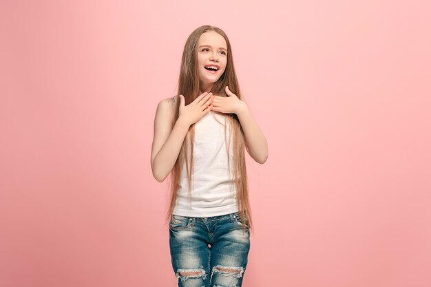 Menina adolescente feliz em pé, sorrindo isolado na parede rosa da moda. Belo retrato feminino de meio corpo. Emoções humanas, conceito de expressão facial.
