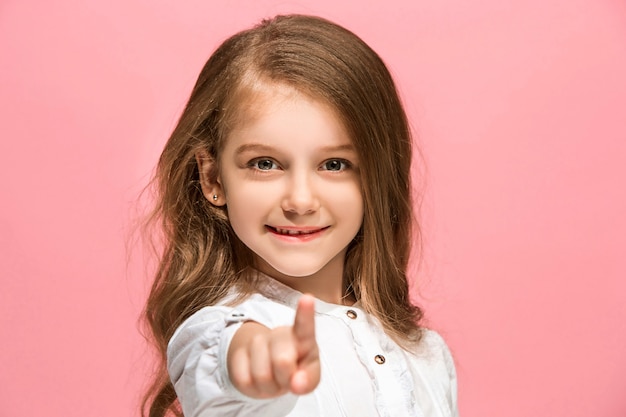 Foto grátis menina adolescente feliz em pé, sorrindo isolado no fundo do estúdio rosa na moda. vista frontal.