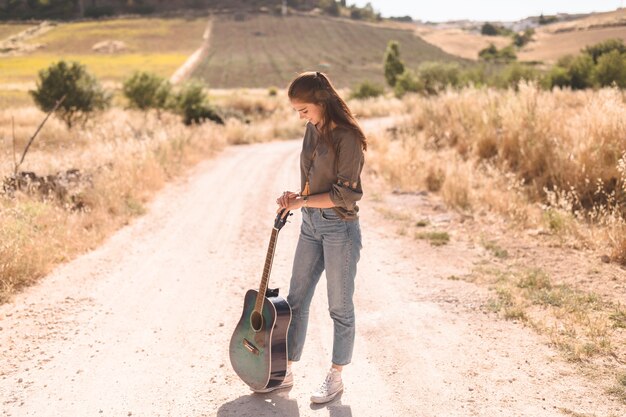 Menina adolescente, ficar, ligado, estrada sujeira, com, guitarra, em, ao ar livre