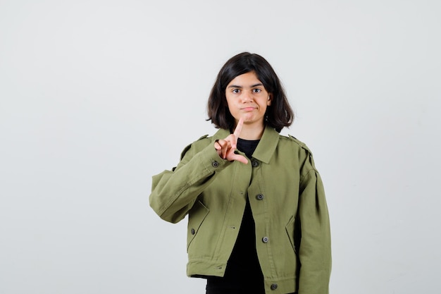 Menina adolescente mostrando sinal de perdedor em t-shirt, jaqueta e parecendo insatisfeito. vista frontal.