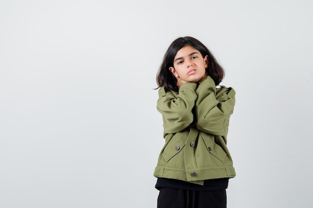 Foto grátis menina adolescente na jaqueta verde do exército, sofrendo de dor de garganta e parecendo angustiada, vista frontal.