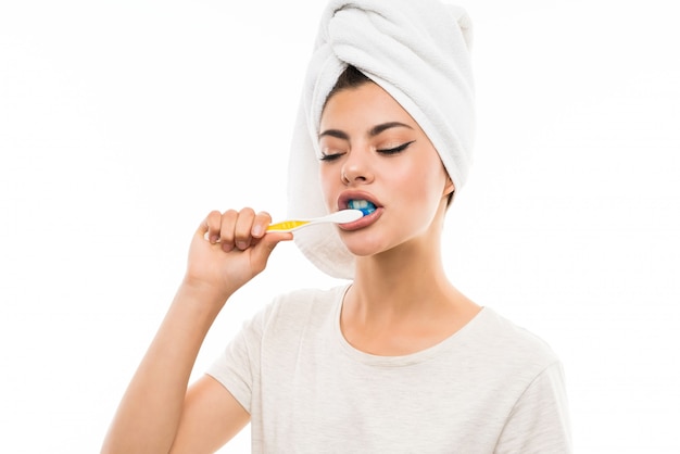 Menina adolescente sobre parede branca isolada, escovando os dentes