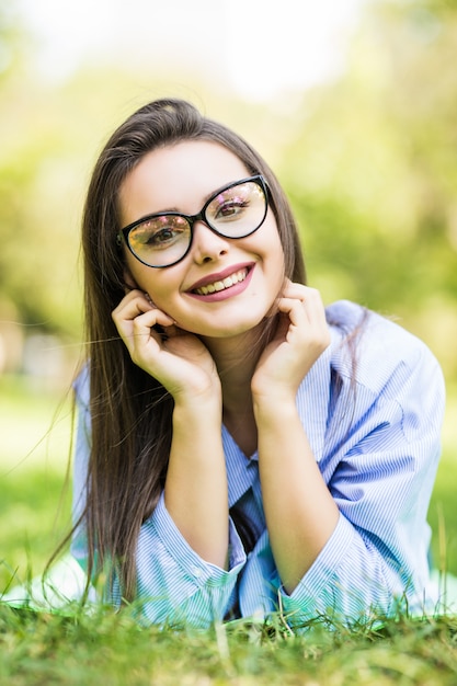 Menina adolescente sonhadora sorridente deitada na grama do parque