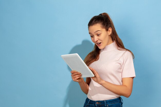 Menina adolescente usando tablet, surpresa e chocada