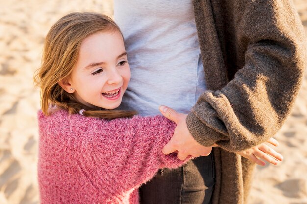 Menina adorável que abraça a mãe tiro médio