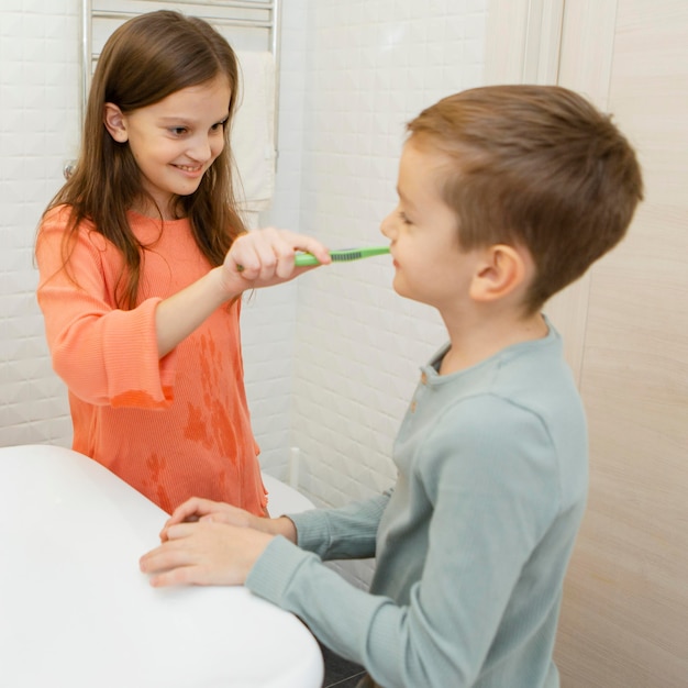 Menina ajudando seu irmão a lavar os dentes