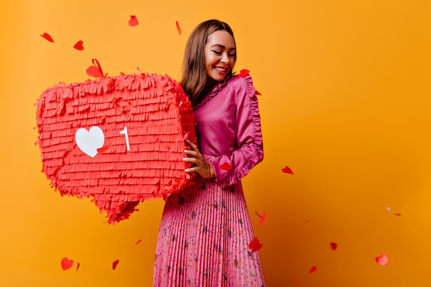 Menina alegre com um lindo sorriso posando com bunner vermelho. refinada morena blogueira feminina de bom humor.