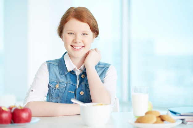 Menina alegre que tem o pequeno almoço em casa