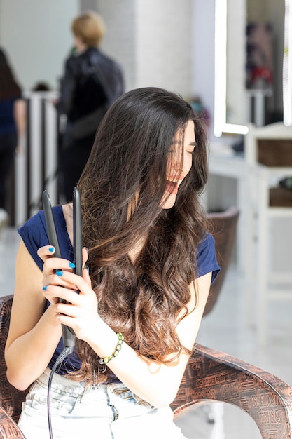 Menina alegre segurando um secador de cabelo e rindo Foto de alta qualidade